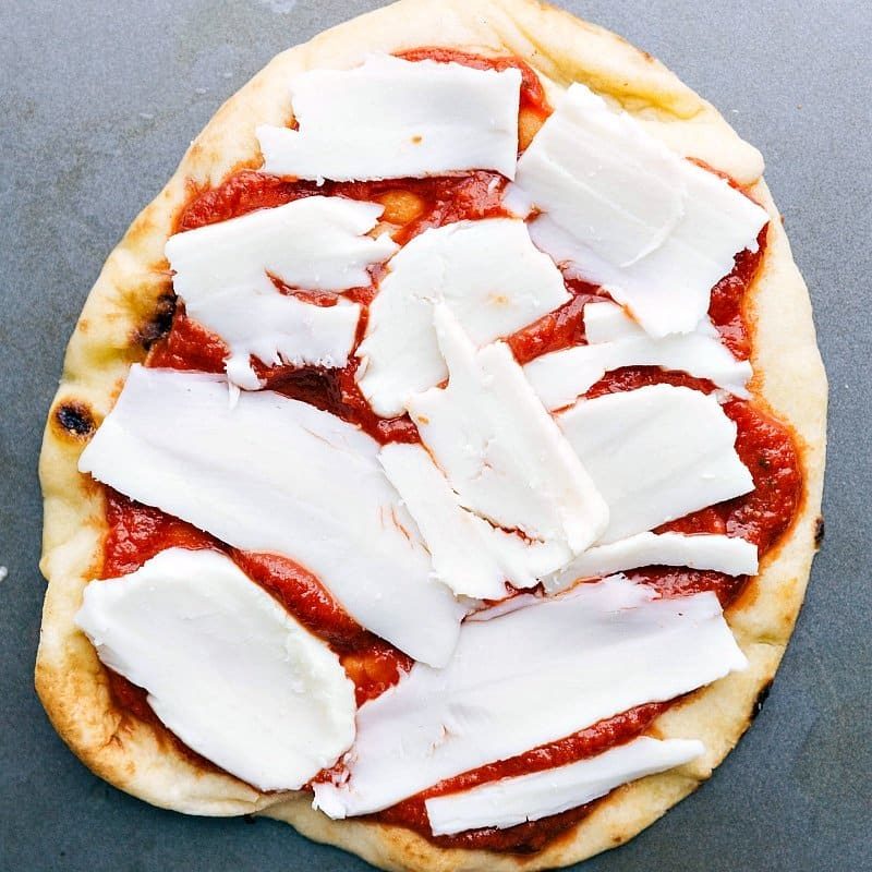 Chunks of fresh mozzarella cheese being added on top of the sauce.