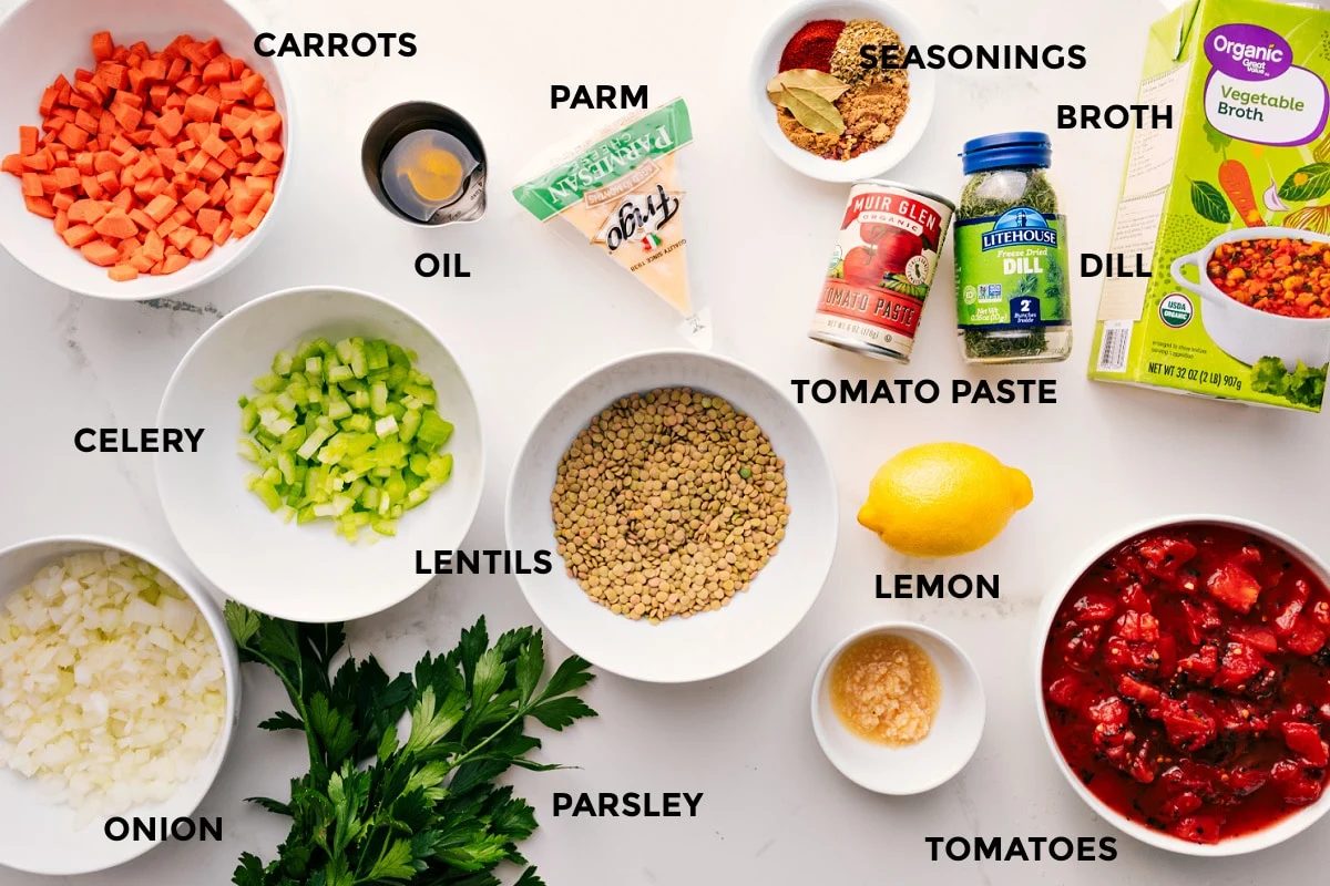 All the ingredients prepped and ready for straightforward assembly, including carrots, celery, onion, lentils, parsley, garlic, tomatoes, lemon, seasonings, tomato paste, dill, and broth.