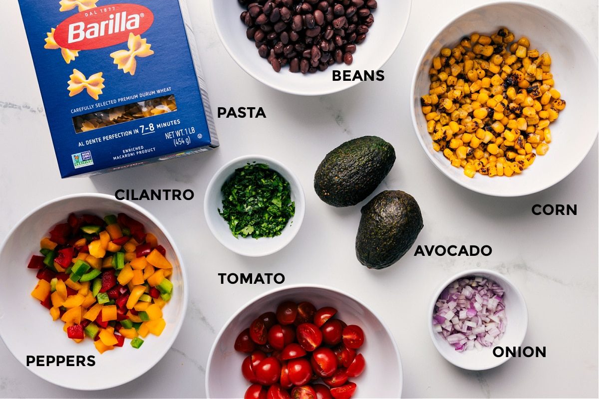 All the ingredients prepped for straightforward assembly—beans, pasta, corn, avocado, onion, tomato, cilantro, and peppers.