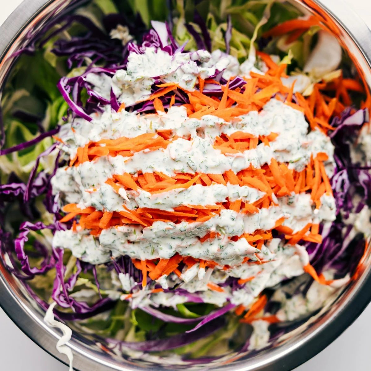 All the ingredients added to a large bowl with the dressing drizzled on top.