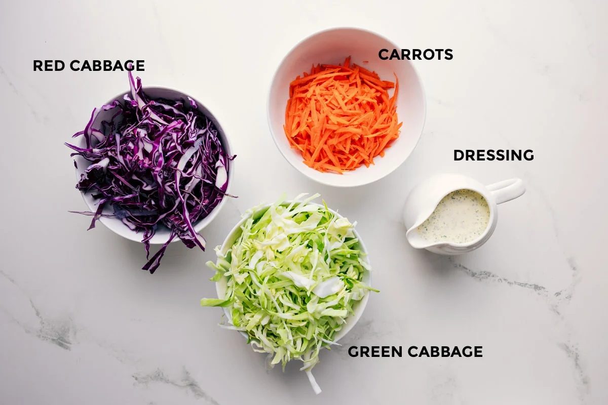 All the ingredients in this recipe prepped out for straightforward assembly including the red cabbage, green cabbage, dressing, and carrots.