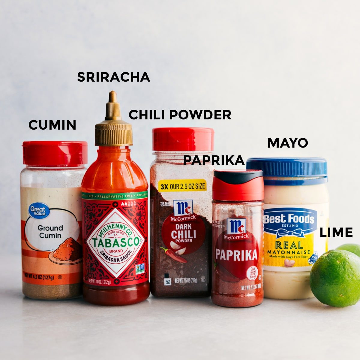 All the dressing ingredients including cumin, sriracha, chili powder, paprika, mayo, and limes prepped out for straightforward assembly.