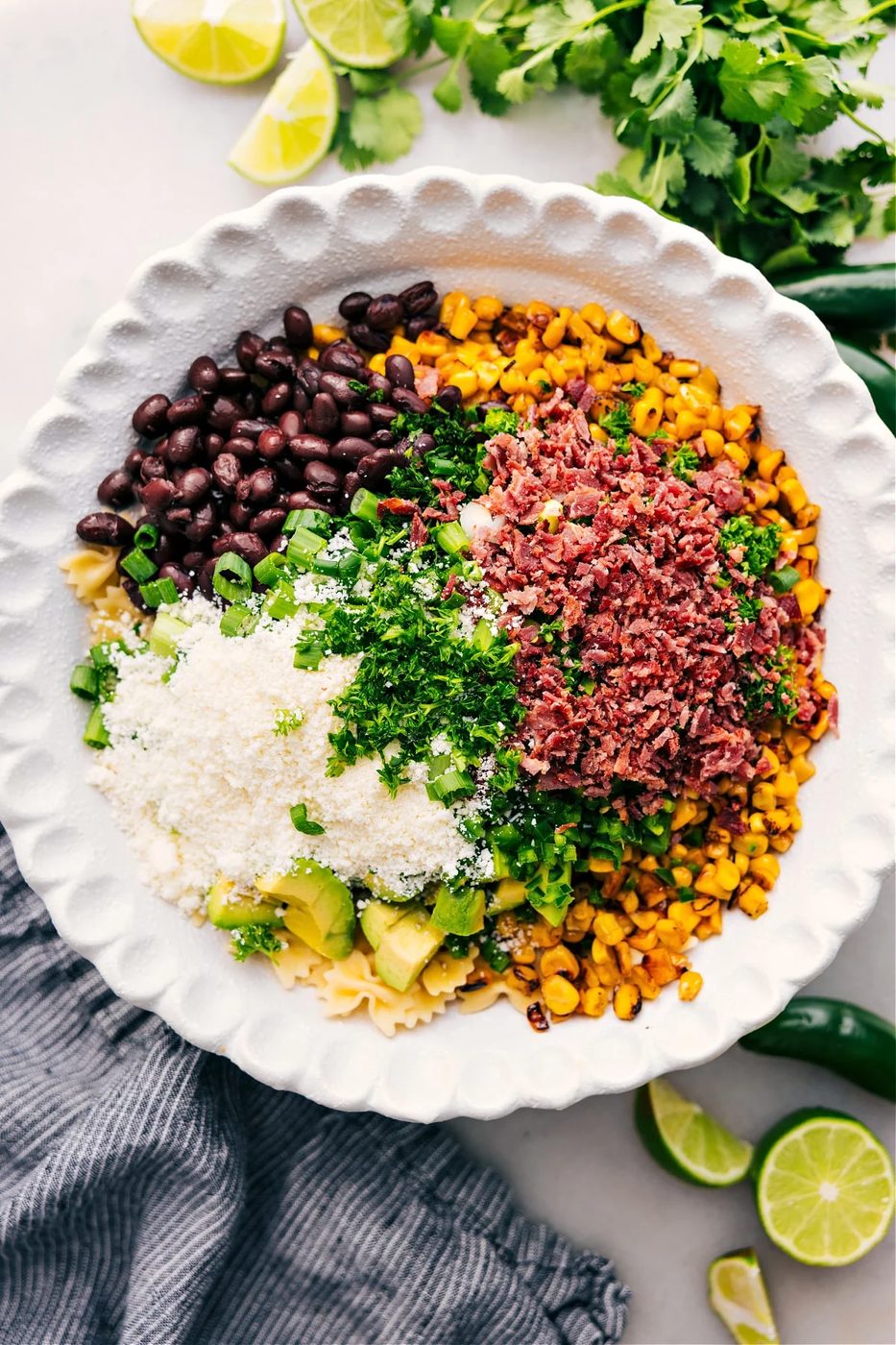 All the ingredients for Mexican Street Corn Pasta Salad added to a bowl, ready to be tossed and dressed with the sauce.