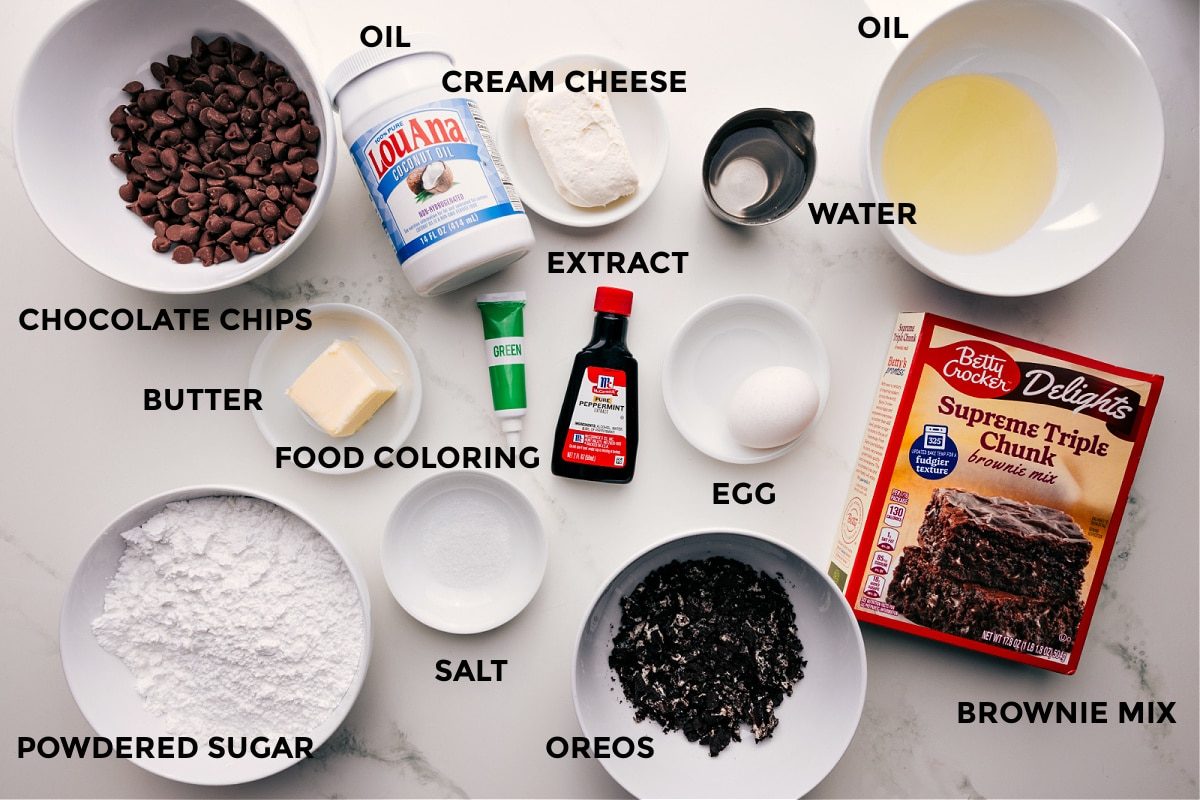 All the ingredients prepped and ready for straightforward assembly, including chocolate chips, butter, food coloring, powdered sugar, salt, oil, cream cheese, extract, Oreos, water, egg, and brownie mix.