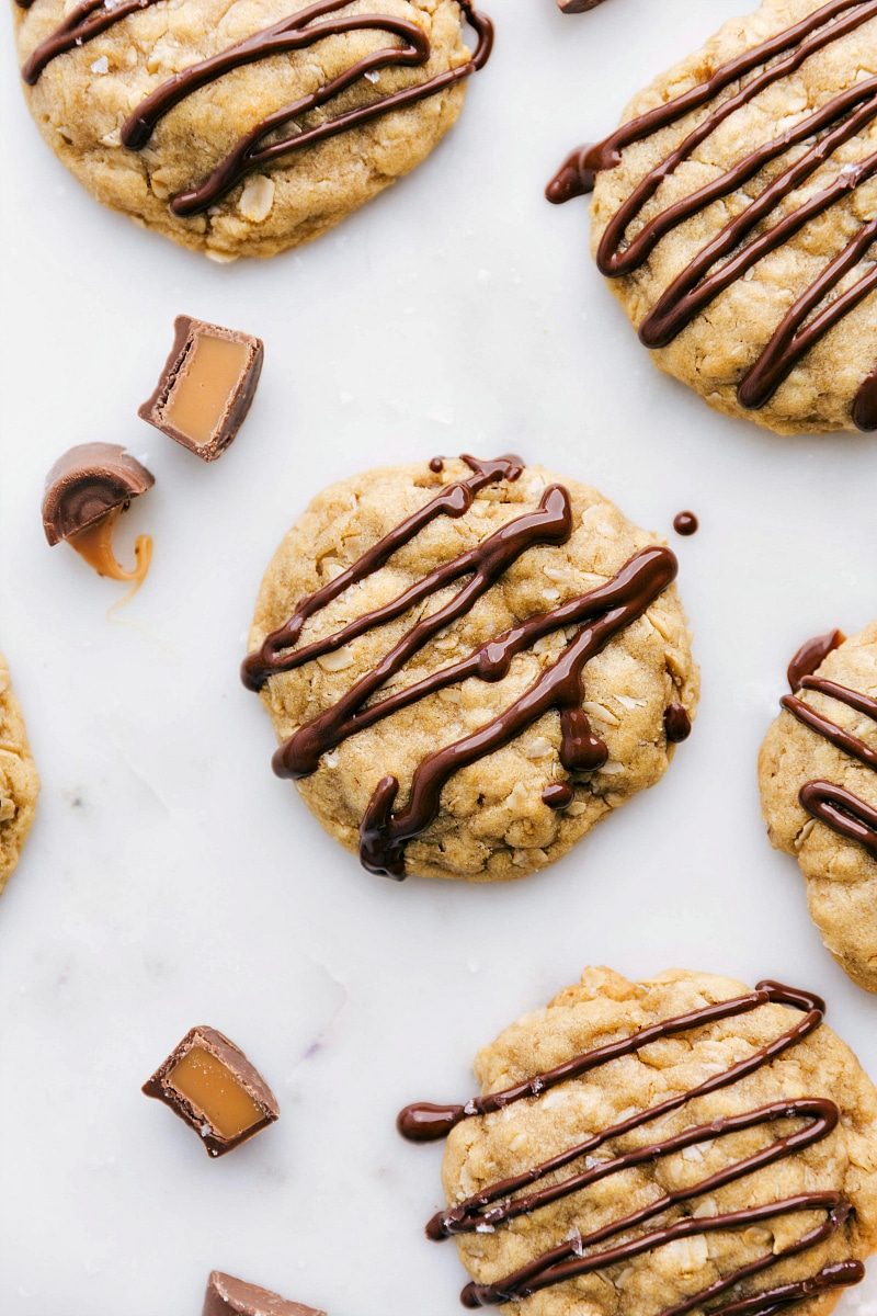 Baked, ready-to-eat salted caramel oatmeal cookies with a drizzle of chocolate on top, showcasing their satisfying and indulgent appearance.