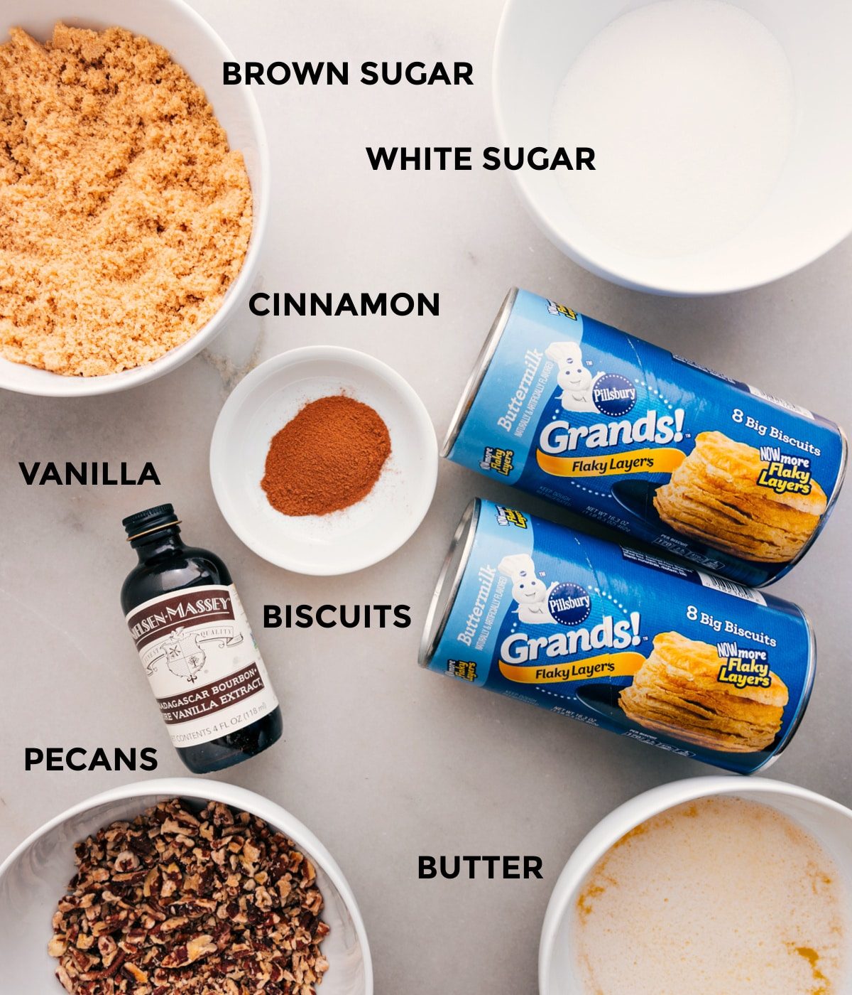 All the ingredients for this recipe are prepped and ready for straightforward assembly: sugars, cinnamon, biscuits, vanilla, pecans, and butter.