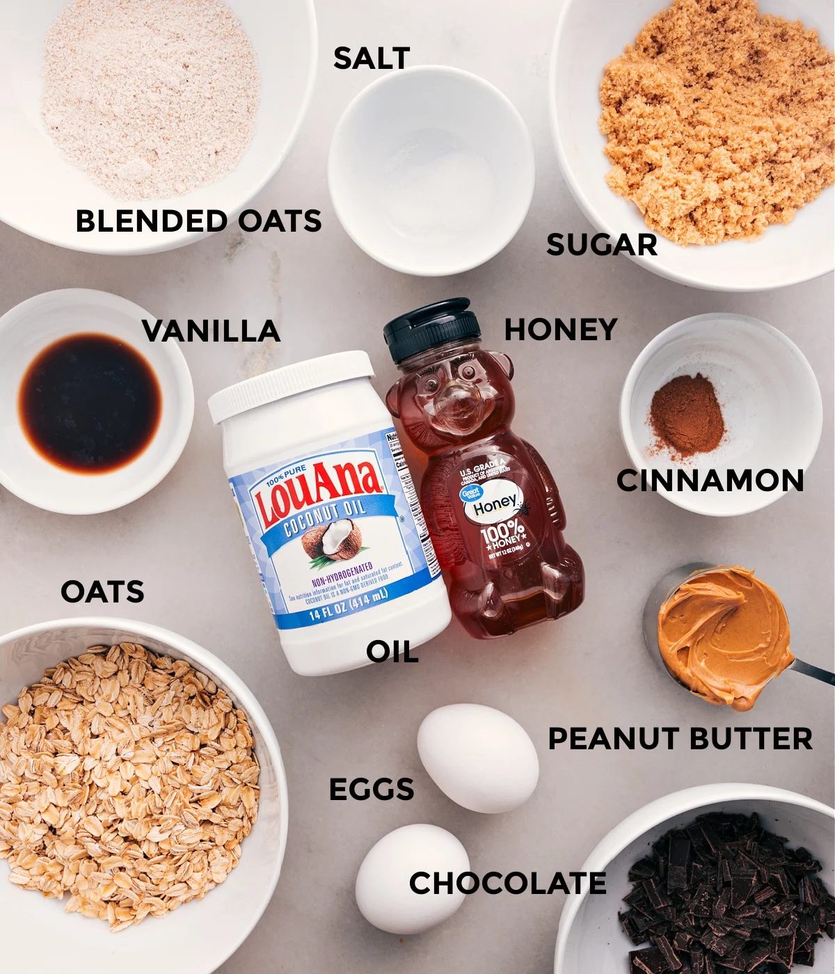 All the ingredients prepped for straightforward assembly—sugar, oats, honey, cinnamon, eggs, peanut butter, oil, vanilla, and chocolate.