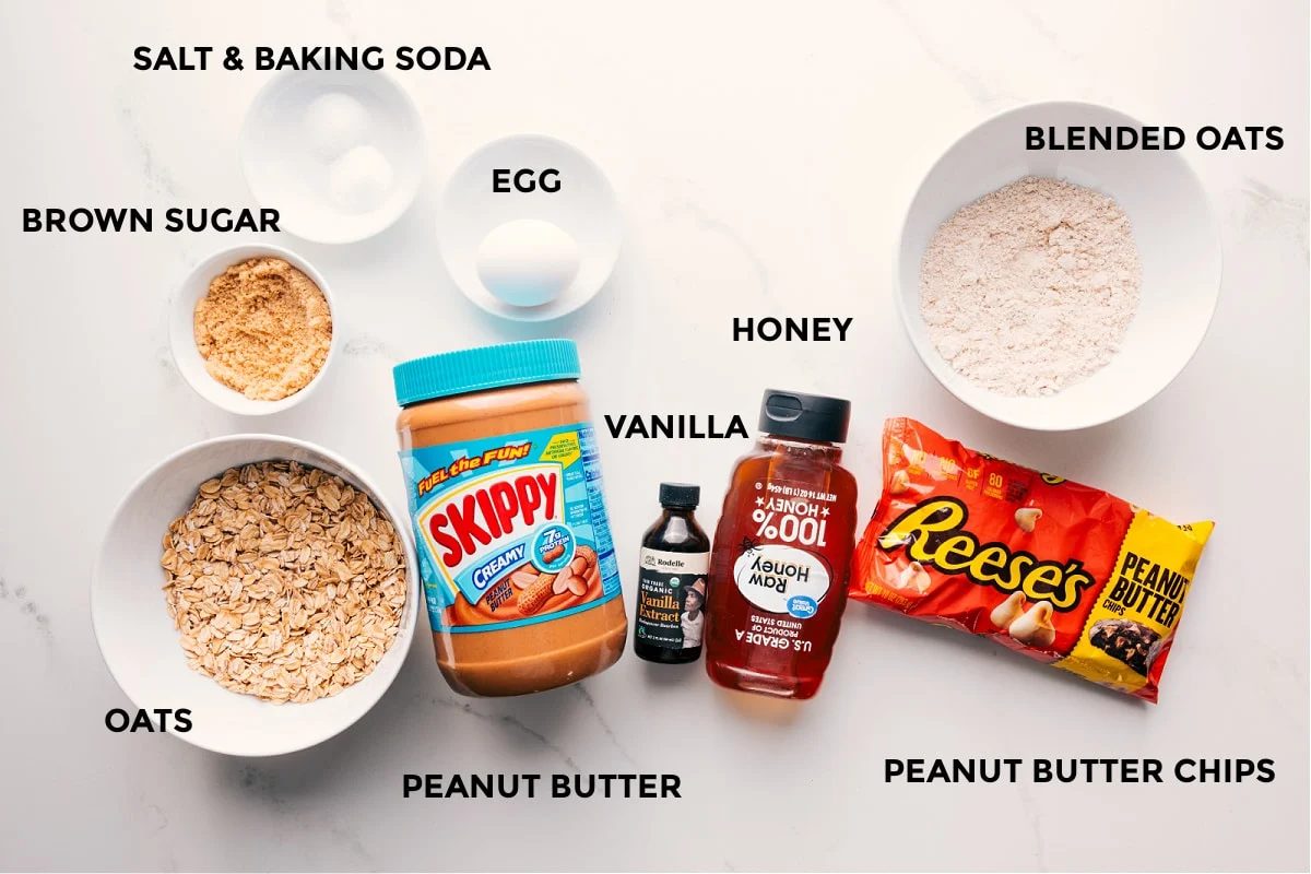 All the ingredients in this recipe prepped out for straightforward assembly including the brown sugar, salt, baking soda, oats, egg, peanut butter, vanilla, honey, blended oats, and peanut butter chips.