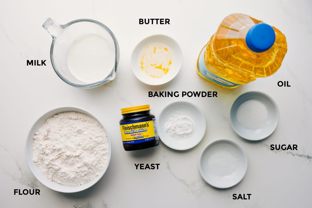 All the ingredients in this recipe prepped out for straightforward assembly including the milk, flour, yeast, baking powder, salt, sugar, oil, and butter.
