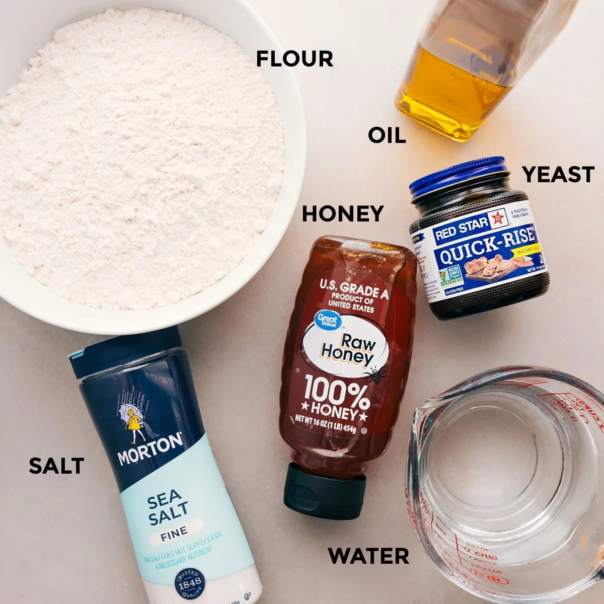 Ingredients for this recipe are prepped for straightforward assembly: flour, oil, yeast, honey, salt, and water.