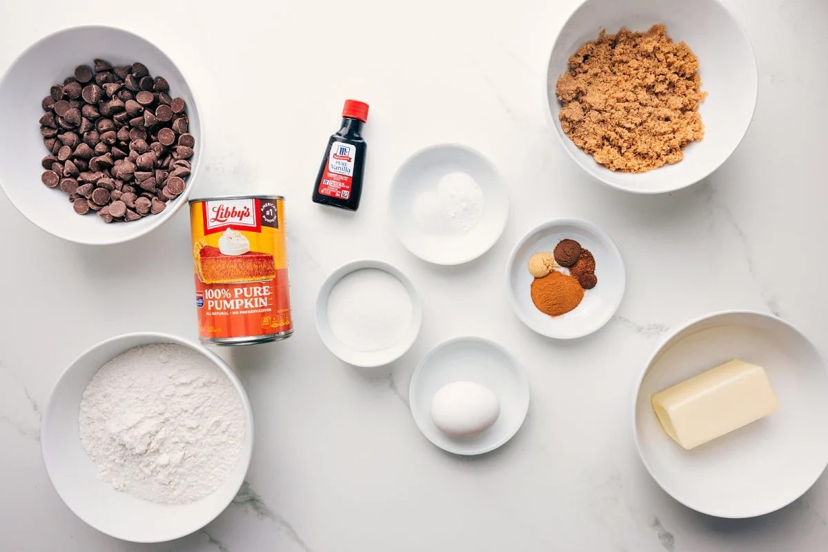 All the ingredients in this recipe prepped out for straightforward assembly including the chocolate chips, flour, pumpkin, vanilla, baking agents, butter, spices, and brown sugar.