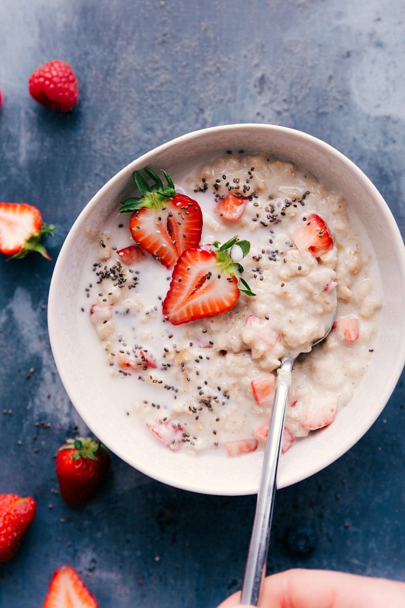 A bowl of creamy strawberries and cream oatmeal recipe, garnished with fresh sliced strawberries.