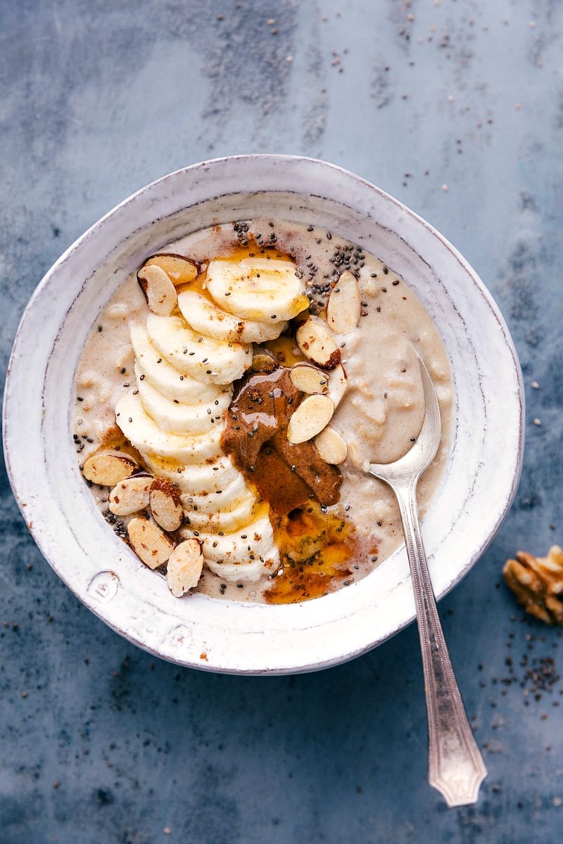 Bowl of peanut butter and banana breakfast, topped with fresh banana slices, sliced almonds, and a drizzle of peanut butter.