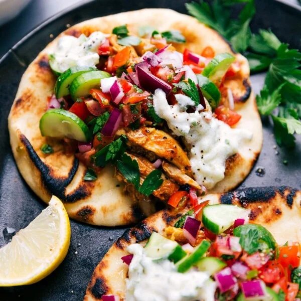 Two finished chicken shawarma wraps topped with satisfying vegetables and sauce.