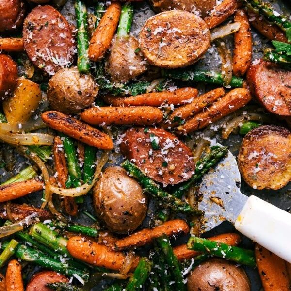 A sheet pan filled with a finished potatoes and sausage dinner, cooked to perfection and seasoned to enhance all the flavors, promising a satisfying meal.