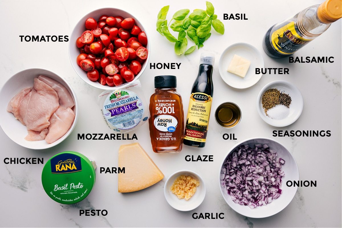 All the ingredients for this recipe are prepped and ready for straightforward assembly, including basil, meat, balsamic, butter, seasonings, onion, oil, glaze, honey, garlic, Parmesan, mozzarella, pesto, and tomatoes.