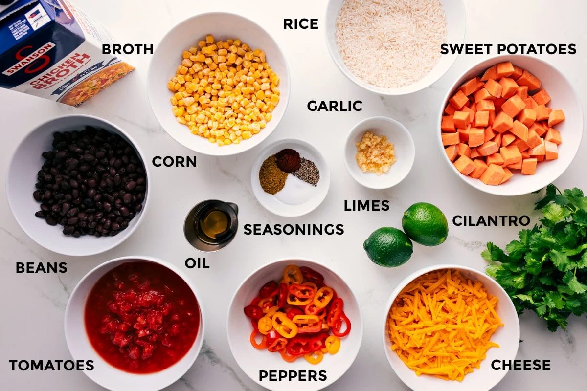 All the ingredients in this recipe prepped out for straightforward assembly including the broth, beans, tomatoes, oil, peppers, cheese, cilantro, limes, sweet potatoes, rice, garlic, seasonings, and corn.