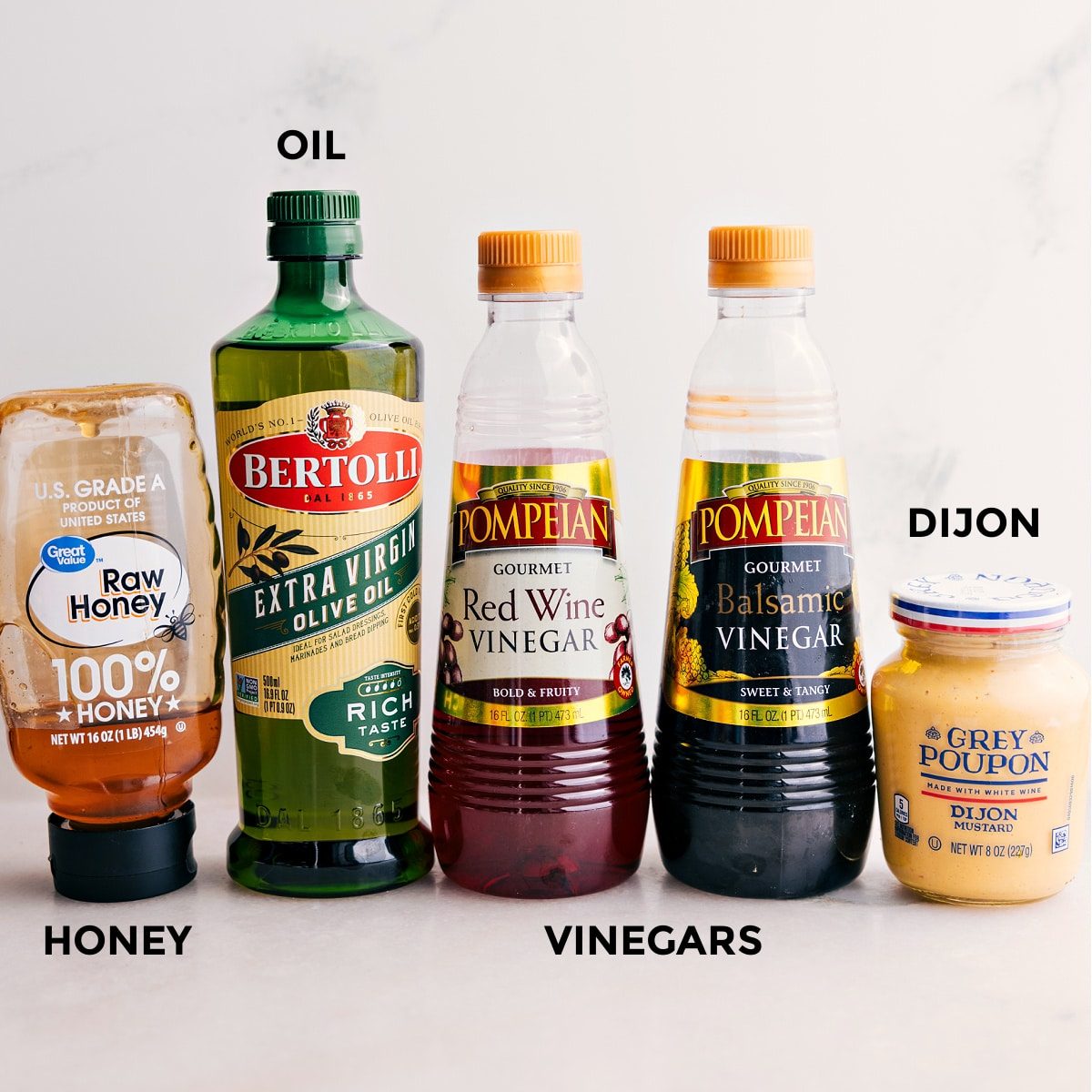 All the dressing ingredients for this panzanella salad are prepped, including honey, oil, red wine vinegar, balsamic vinegar, and Dijon.