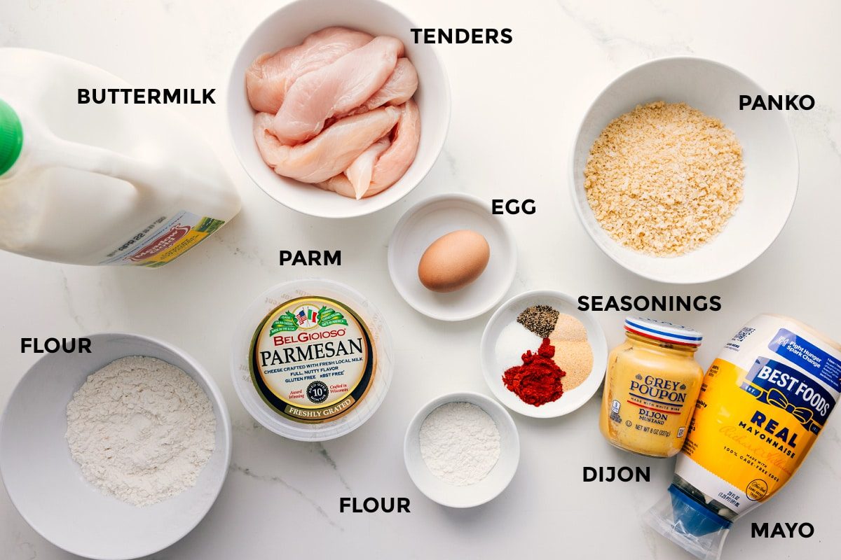 All the ingredients in this recipe prepped out for straightforward assembly including the buttermilk, meat, parm, flour, seasonings, egg, dijon, mayo, and panko.