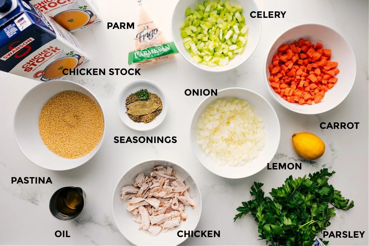 All the ingredients in this recipe prepped out for straightforward assembly including chicken stock, pastina, oil, parm, seasonings, chicken, and veggies.