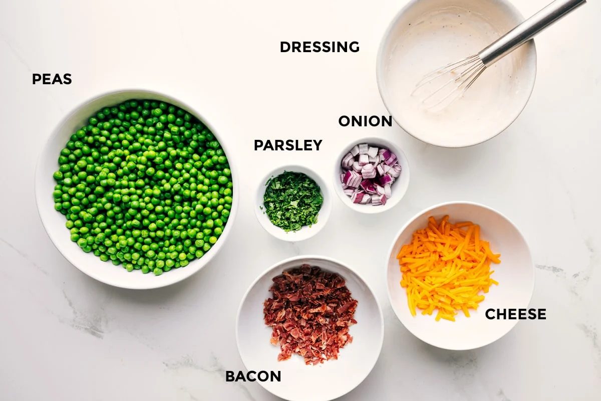 All the ingredients in this recipe prepped out for straightforward assembly including the peas, parsley, onion, cheese, bacon, and dressing.