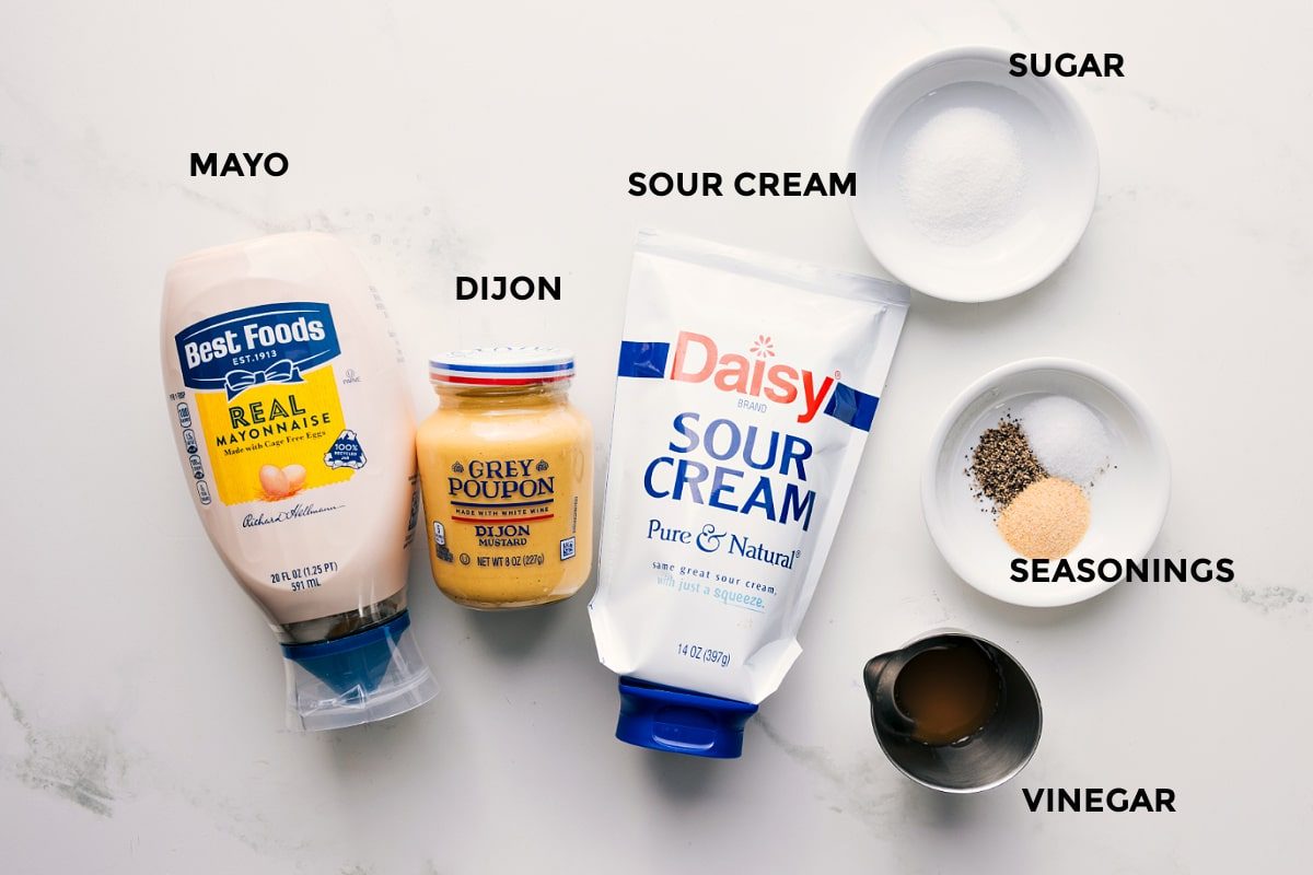 The dressing ingredients for this pea salad recipe prepped for straightforward assembly including mayo, Dijon mustard, sour cream, sugar, vinegar, and seasonings.