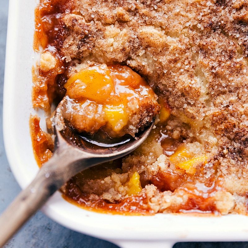 A spoonful of the dessert being scooped out of the casserole dish, revealing the satisfying fruity interior.