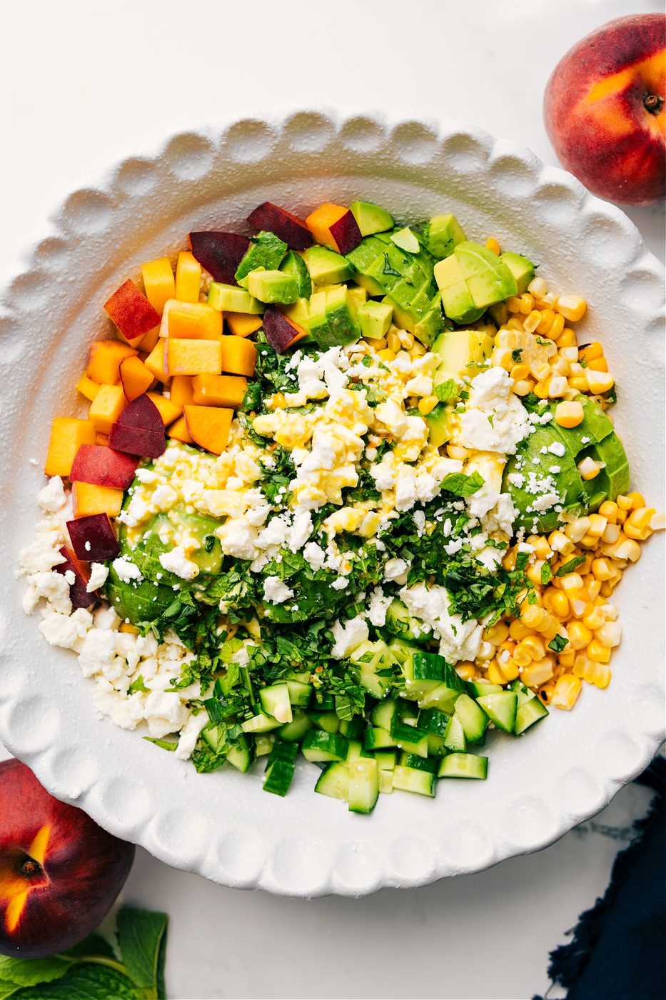 Peach feta salad in a bowl drizzled with dressing ready to be tossed together and enjoyed.