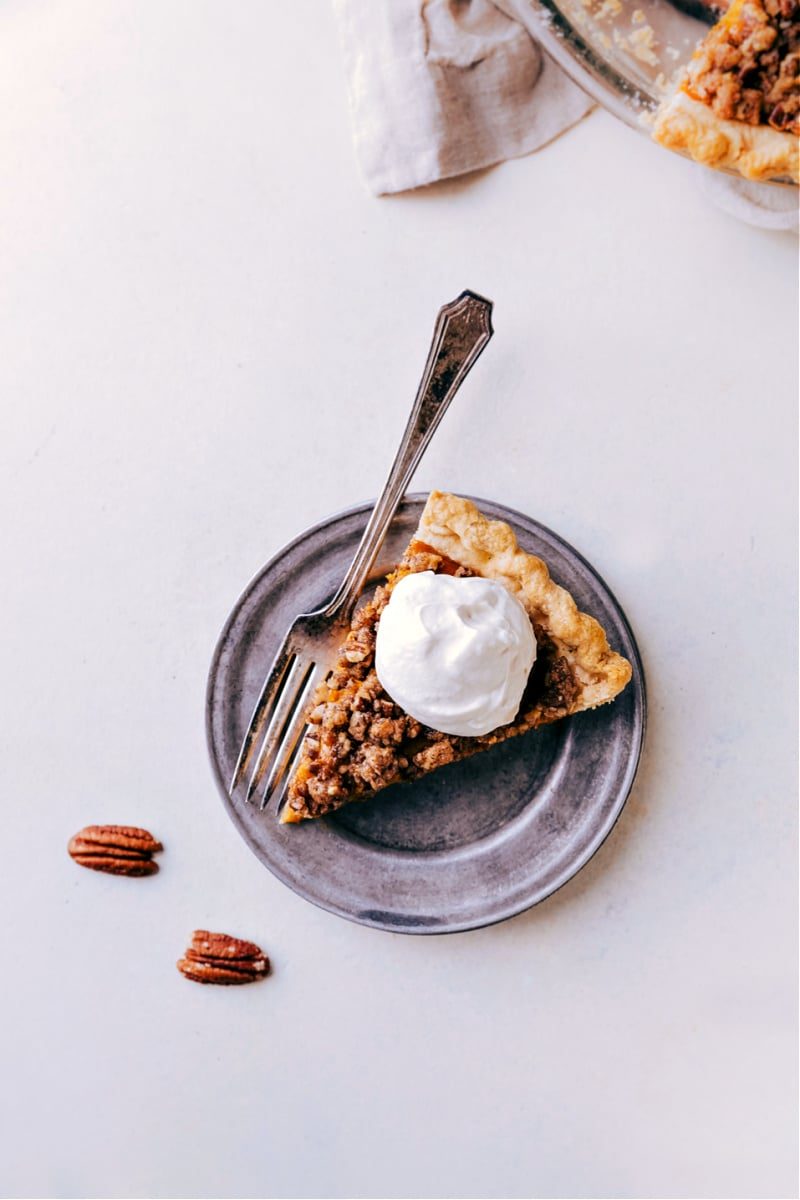 Pumpkin pecan pie slice topped with maple whipped cream.