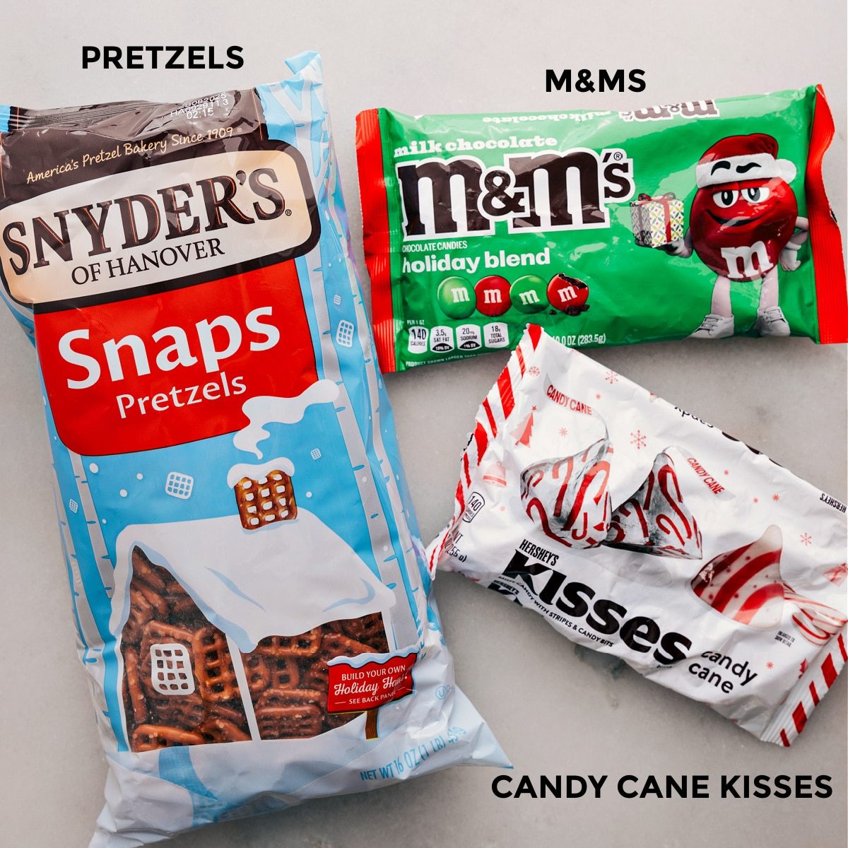The three ingredients for this recipe—pretzels, M&Ms, and chocolate kisses—are prepped and ready for straightforward assembly.