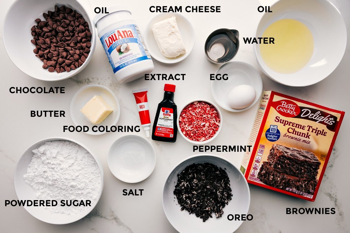 All the ingredients in this recipe prepped out for straightforward assembly including chocolate, butter, food coloring, salt, powdered sugar, Oreo, cream cheese, peppermint, extract, egg, oil, water, and brownie mix.