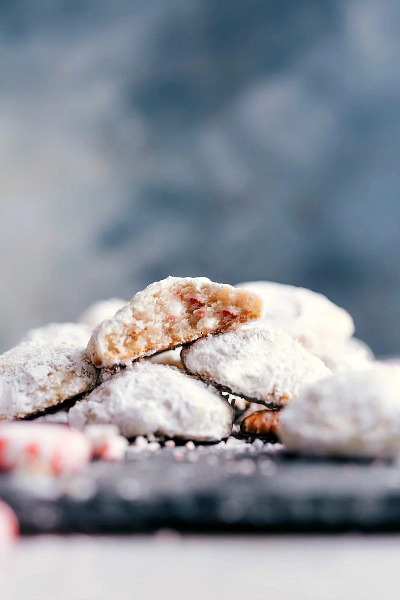 Finished snowball cookies with peppermint, satisfying and flavor-packed, with a bite taken out to reveal the delightful interior.