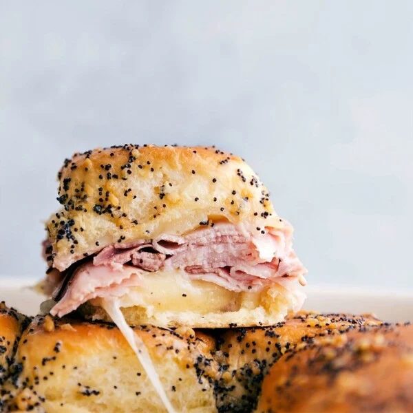 Ham and cheese sliders stacked on top of each other showing the satisfying inside.