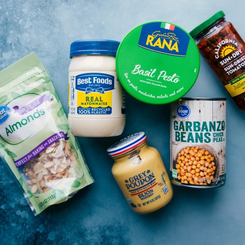 Ingredients prepped for straightforward assembly, including pesto, tomatoes, mayo, almonds, garbanzo beans, and Dijon mustard.