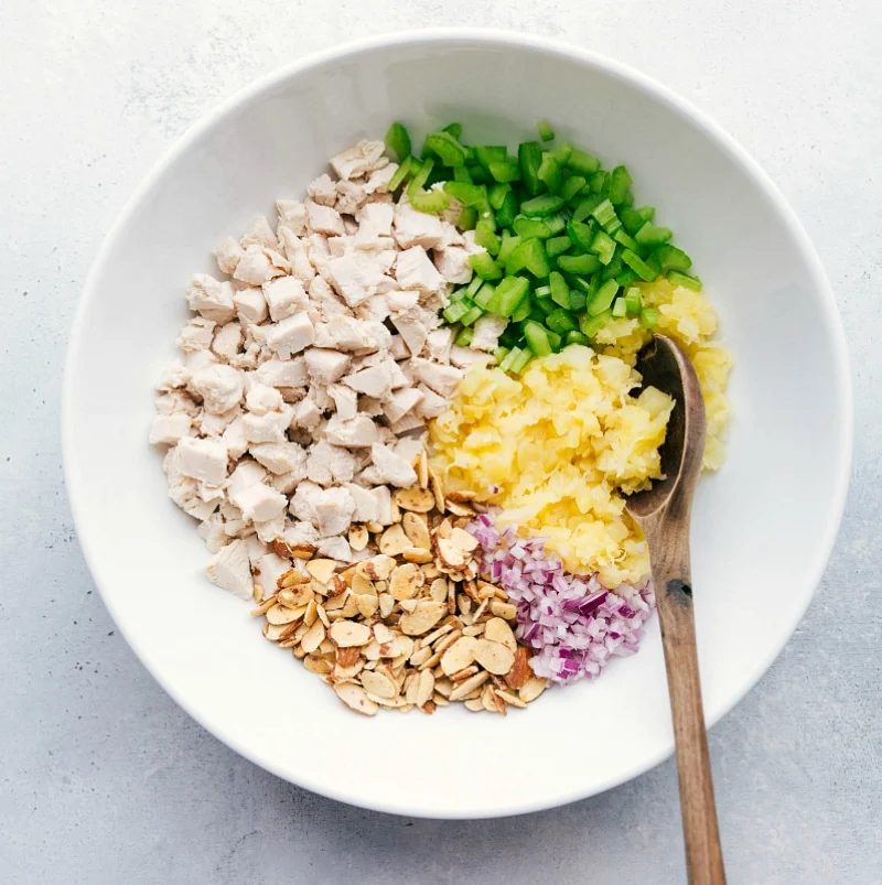 A bowl filled with chicken, pineapple, and other ingredients, ready to be mixed together for a flavorful dish.