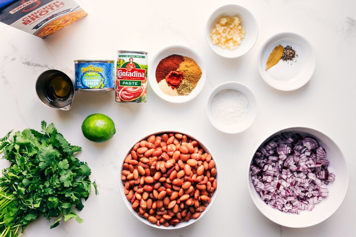 All the ingredients in this recipe prepped out for straightforward assembly including the broth, cilantro, lime, oil, beans, onion, seasonings, garlic, green chiles, and flour.