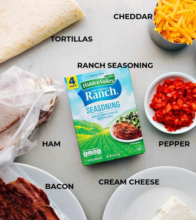All the ingredients in this recipe prepped out for straightforward assembly including the tortillas, ham, bacon, ranch seasoning, cream cheese, peppers, and cheese.