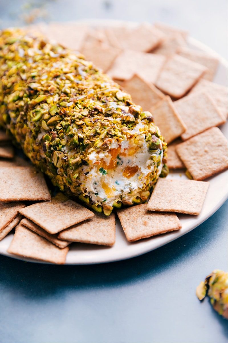 Up-close image of the pistachio goat cheese ball on a plate with crackers on the side ready to be enjoyed