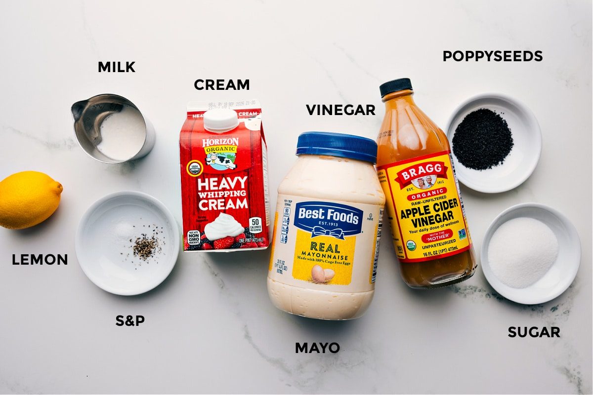 All the ingredients in this recipe prepped out for straightforward assembly including the lemon, milk, cream, seasonings, cream, vinegar, poppyseeds, and sugar.