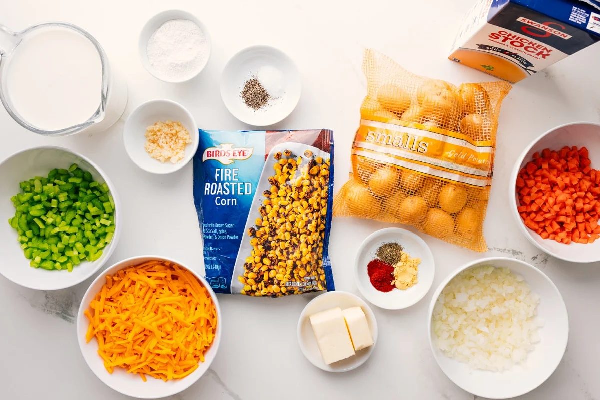 All the ingredients in this recipe prepped out for straightforward assembly including milk, veggies, cheese, corn, butter, seasonings, garlic, and chicken stock.