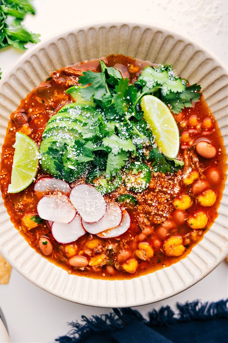 30-minute Mexican inspired Pozole Recipe in a bowl with avocado, cilantro, and limes on the top.