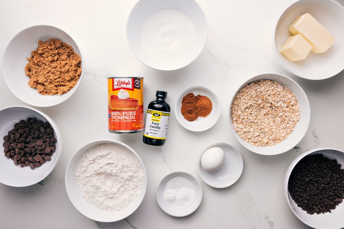 All the ingredients in this recipe prepped out for straightforward assembly including chocolate chips, sugar, vanilla, pumpkin, oats, eggs, baking agents, and butter.