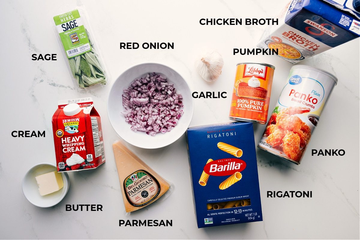 All the ingredients in this recipe prepped for straightforward assembly, including butter, cream, parmesan, sage, red onion, garlic, rigatoni, panko, pumpkin, and broth.