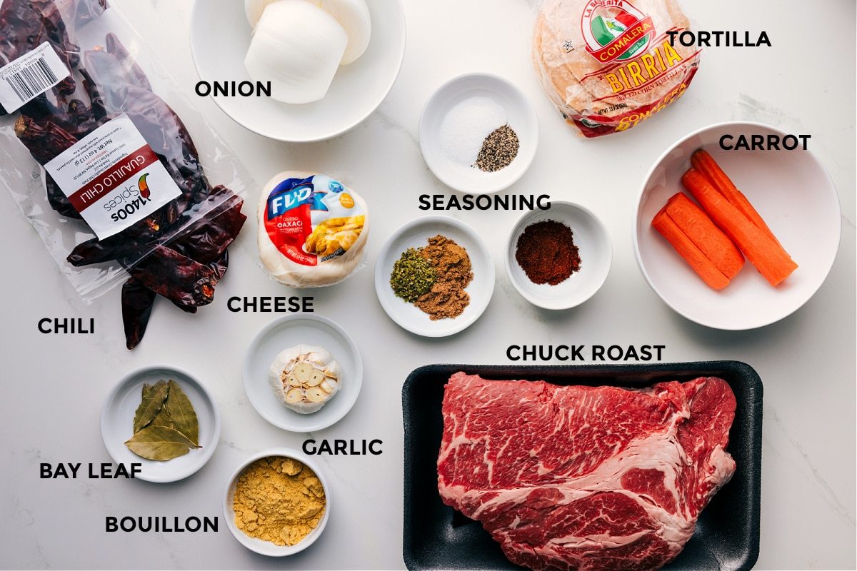 All the ingredients for this recipe prepped and ready for straightforward assembly: onion, chilis, tortillas, carrot, seasonings, cheese, chuck roast, garlic, and bouillon.