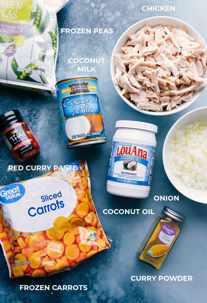 All the ingredients for this recipe prepped and laid out for straightforward assembly, including peas, coconut milk, shredded chicken, red curry paste, coconut oil, diced onions, sliced carrots, and seasonings.