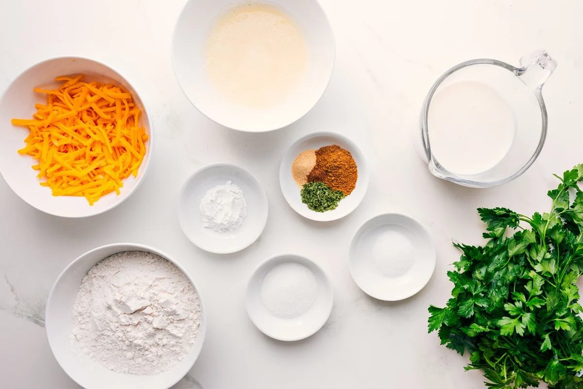 All the ingredients in this recipe prepped out for straightforward assembly including the cheese, flour, seasonings, buttermilk, butter, parsley, and flour.