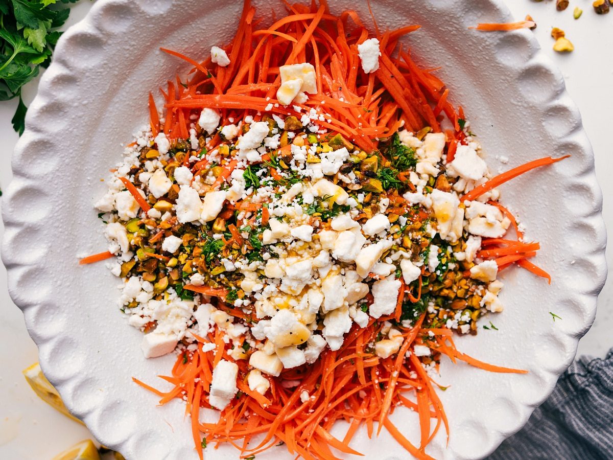 Ribbon carrot salad ingredients added to a bowl before tossing together.