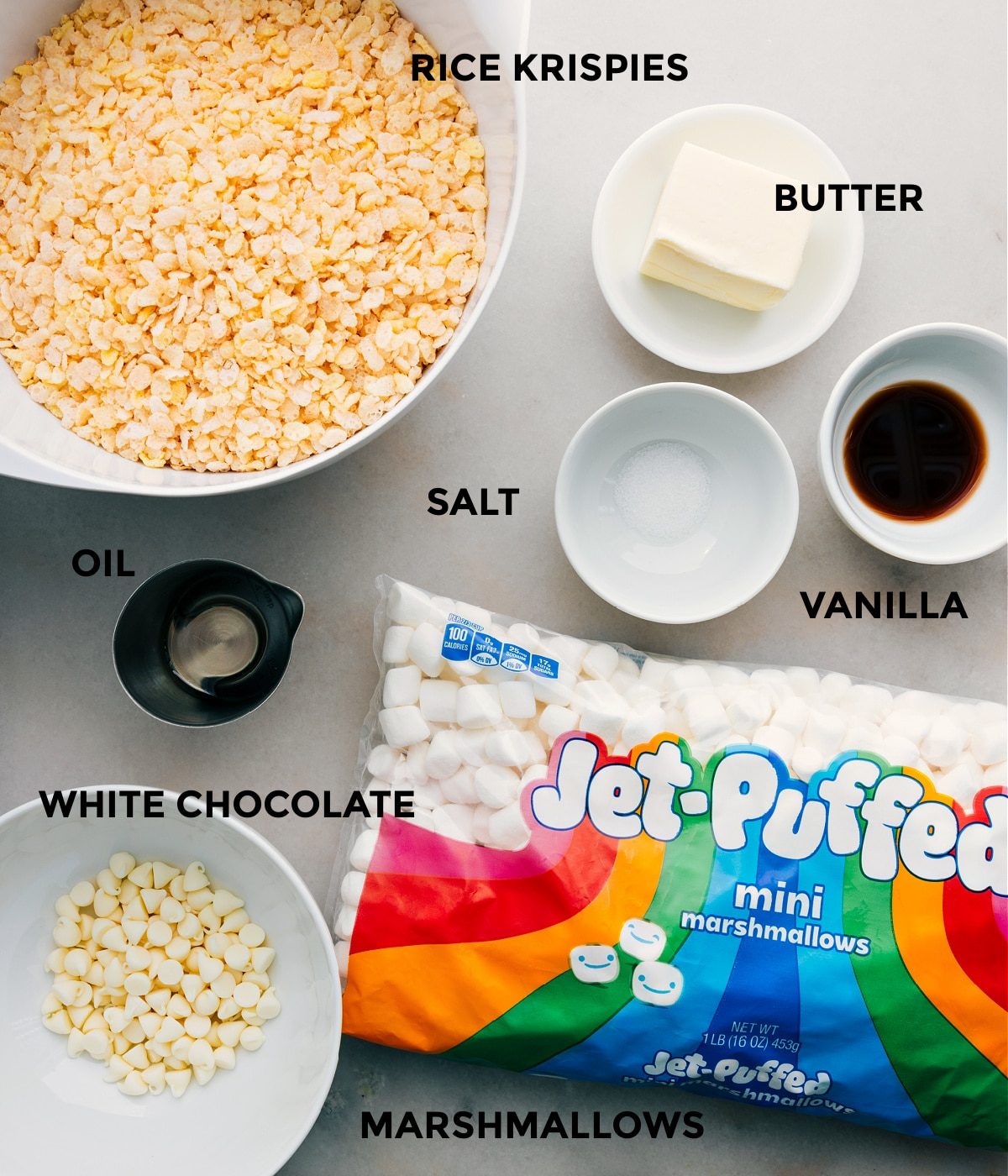 All the ingredients including cereal, butter, vanilla, salt, oil, white chocolate, and marshmallows in this recipe prepped out for straightforward assembly.