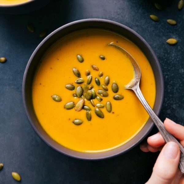 Carrot Soup in a bowl garnished with pepita seeds, a healthy and satisfying meal.