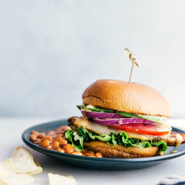 A chicken burger on a plate accompanied by a side of baked beans, presenting a satisfying and satisfying meal, ready for enjoyment.